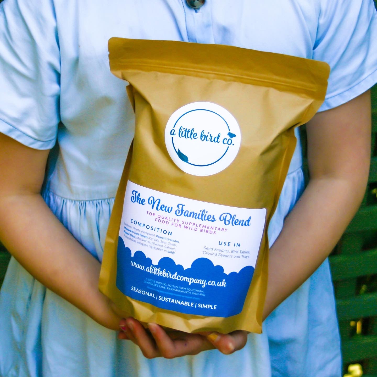 Child holding bag of seasonal A Little Bird Co. bird food.